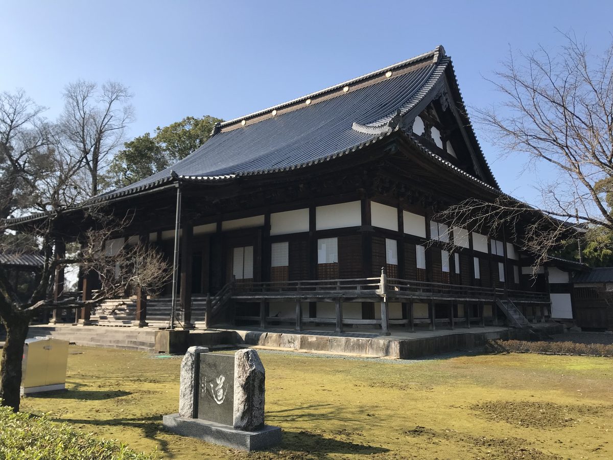The main hall of Zendoji in Kurume, seen across a moss-covered courtyard with a stone monument in front.